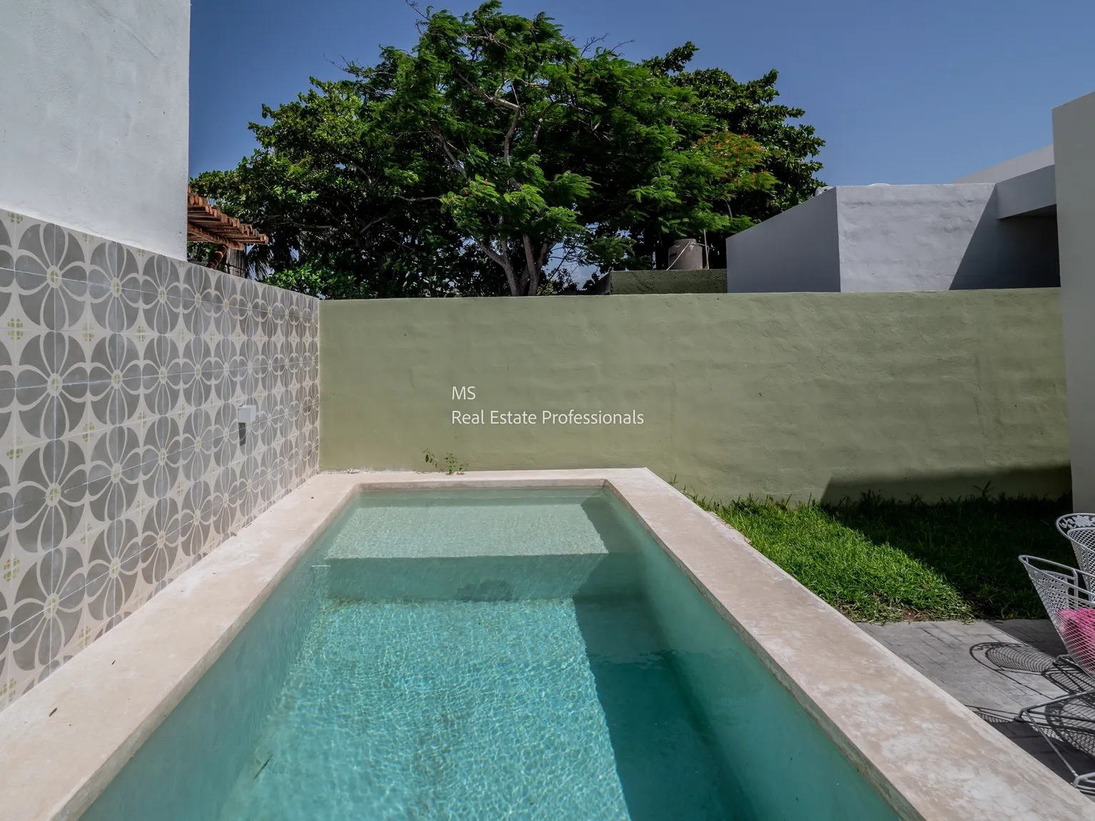 A pool with a wall and grass in the background