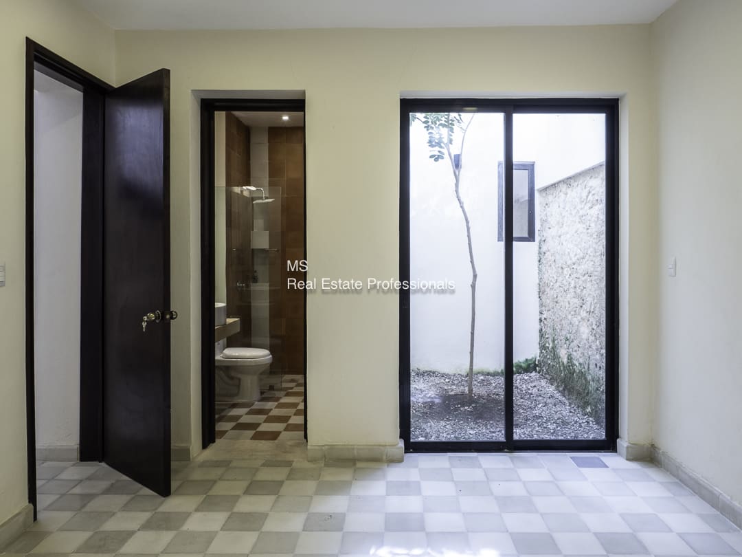 A bathroom with an open door and a sliding glass door leading outside.