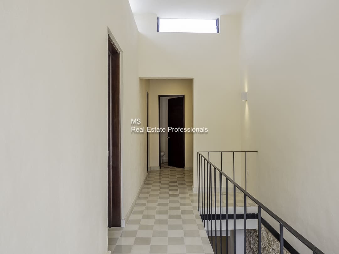 Narrow indoor corridor with a window and railing.