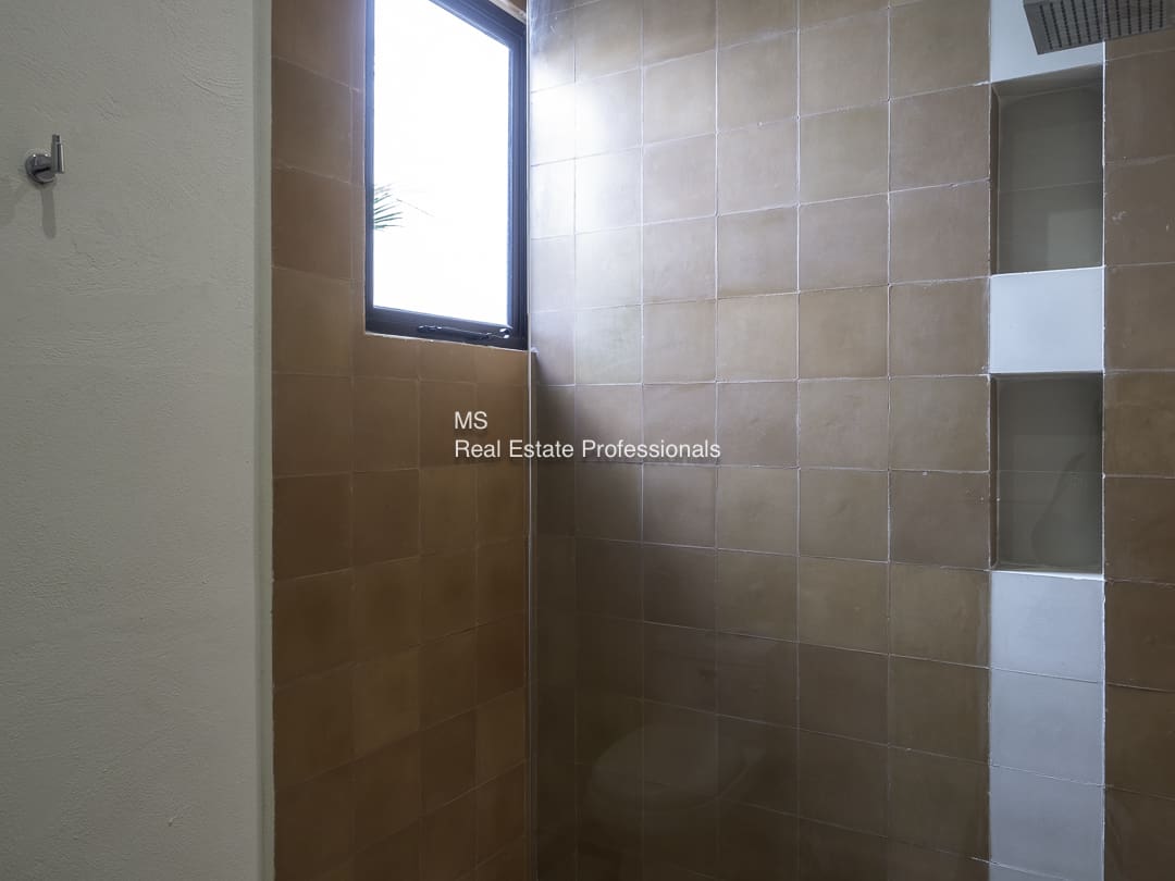 A small window above beige tiled bathroom walls.