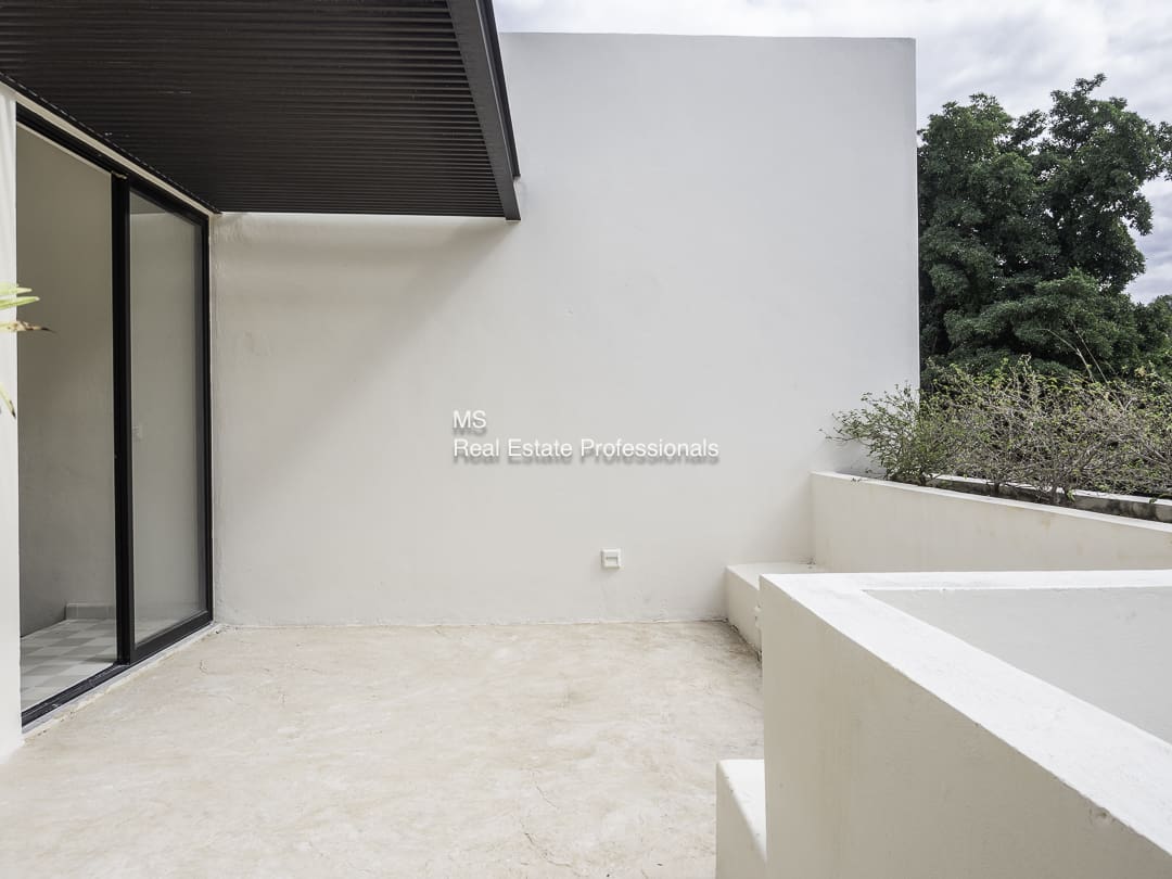 Minimalist outdoor space with white walls and a shadowed ceiling corner.
