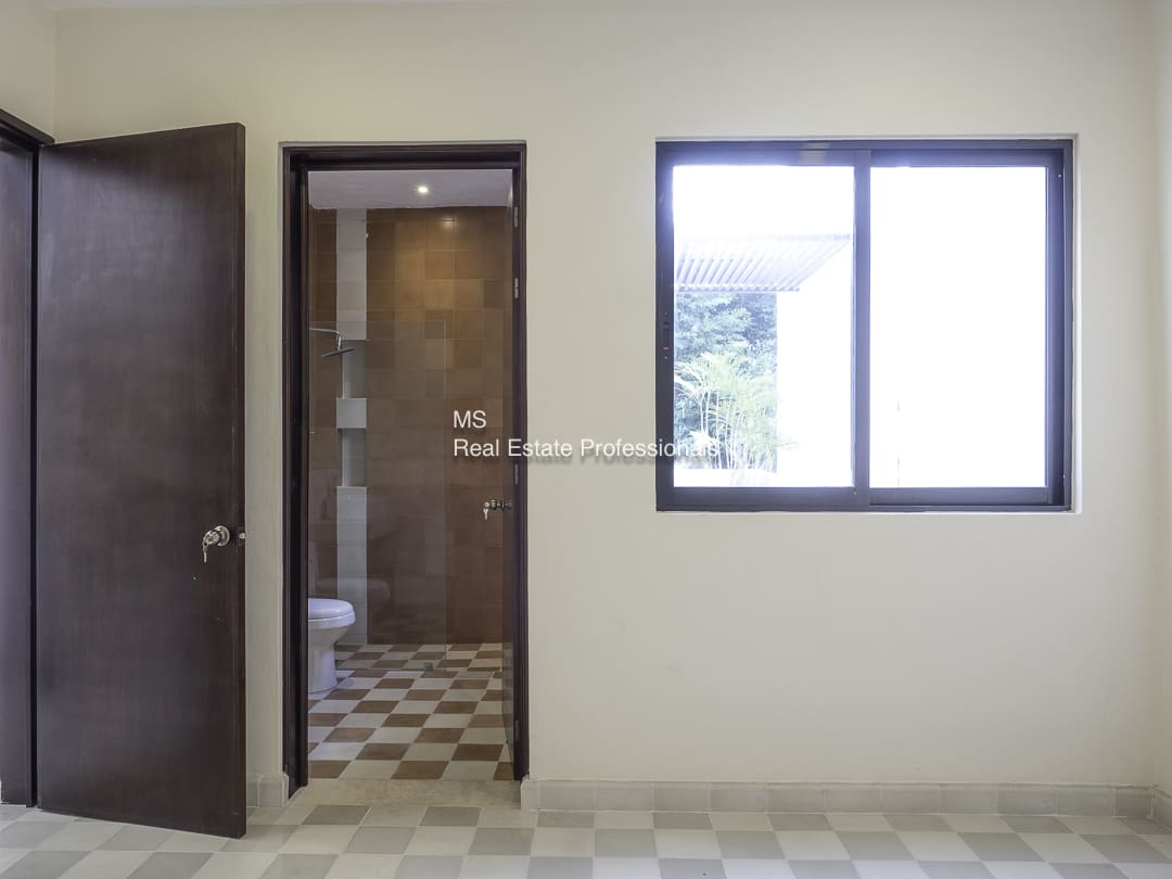 Empty room with tiled floor and doorway to bathroom.