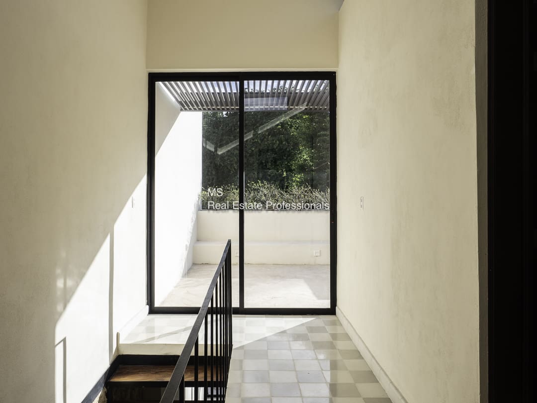 Sunlight streams through a glass door at the top of a stairwell.