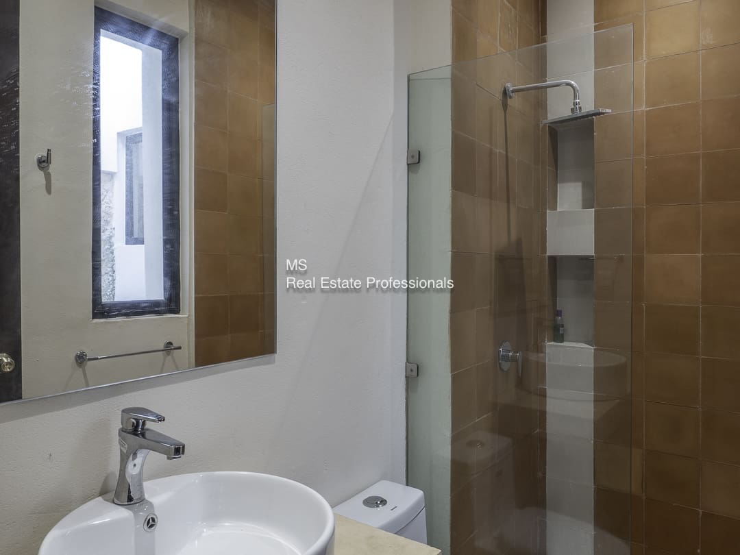 Modern bathroom with a sink, toilet, and glass shower enclosure.
