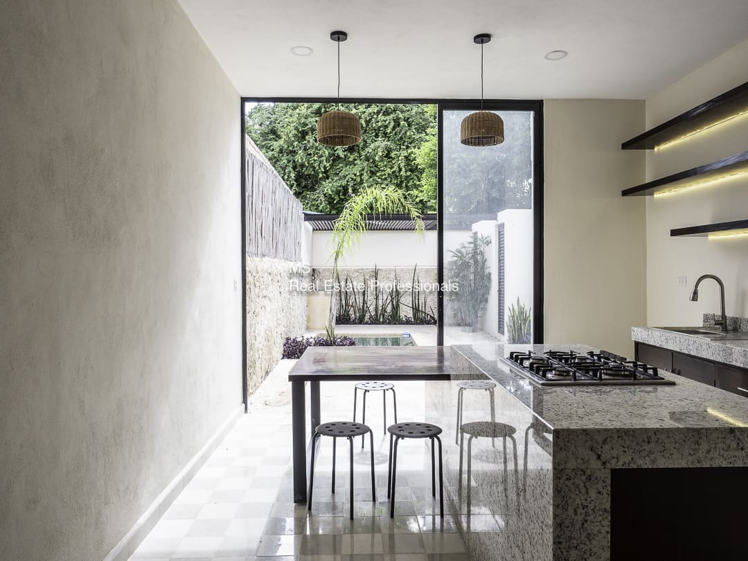 Minimalist kitchen with a dining table and stools by a large window.
