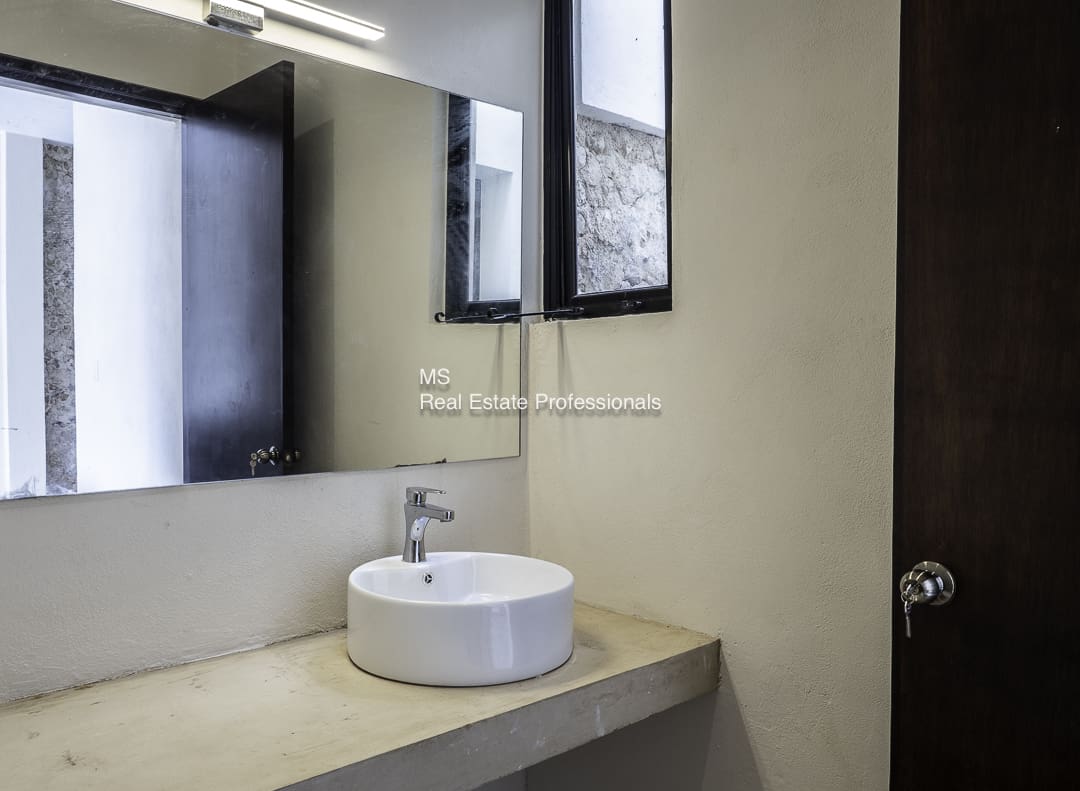 Modern bathroom with a round sink and large mirror.