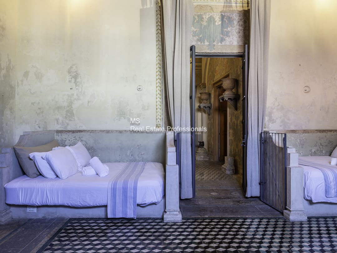 A white sofa with folded towels next to a rustic door in a vintage room.