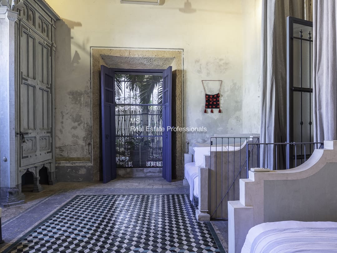 Interior view of a historic building with patterned floor tiles and grand staircases.
