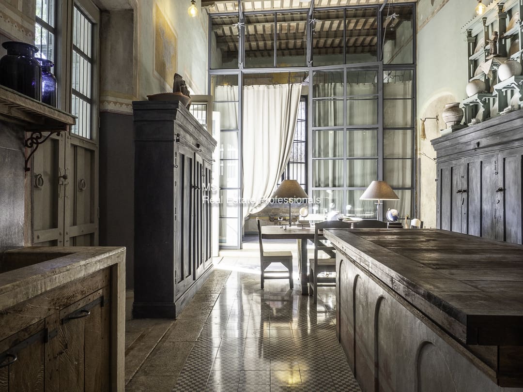 A rustic kitchen with vintage furniture and hanging light fixtures.