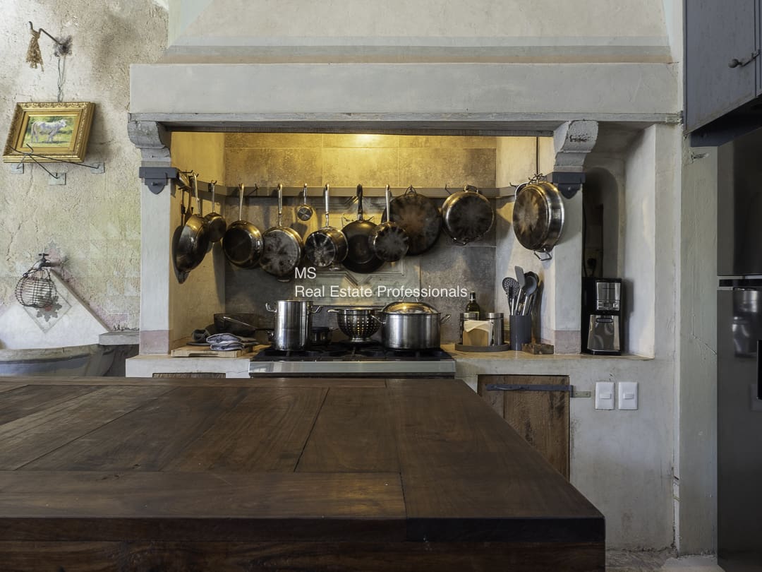 A kitchen with pots hanging above the stove and cooking utensils.