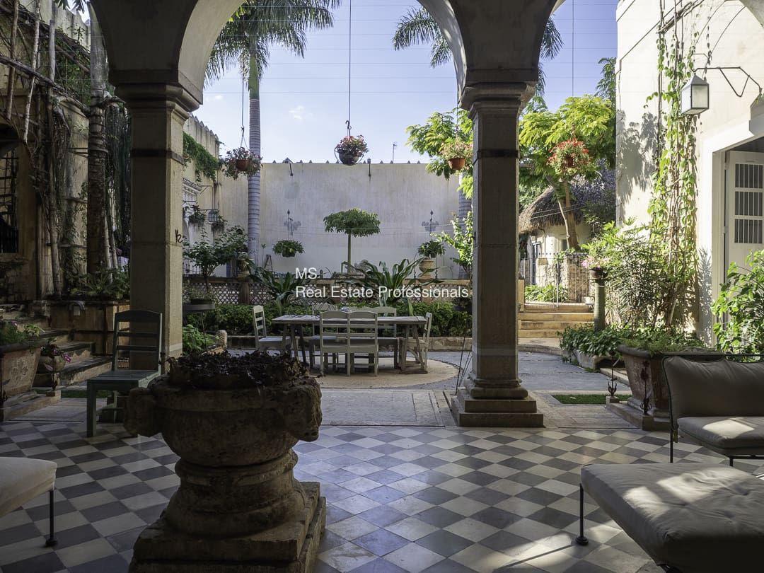 A serene courtyard with arches, plants, and seating.