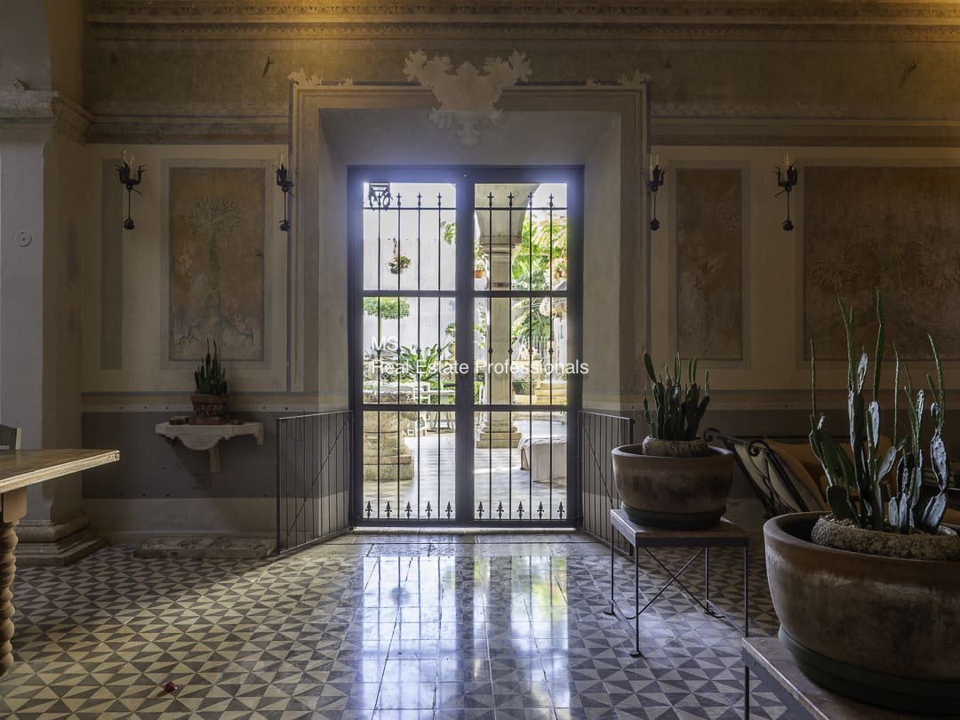 A sunlit ornate doorway with patterned floor tiles.