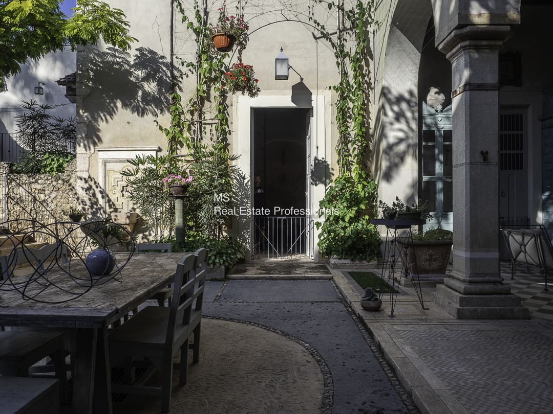 A serene courtyard with climbing plants and rustic furniture.