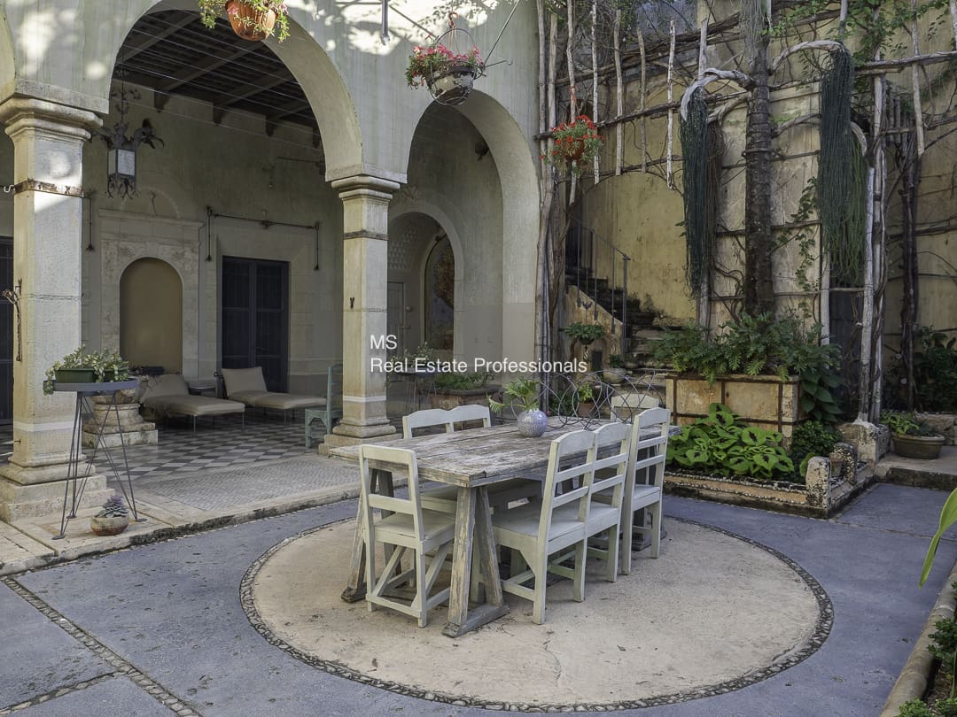 Outdoor dining area with rustic furniture and stone arches.
