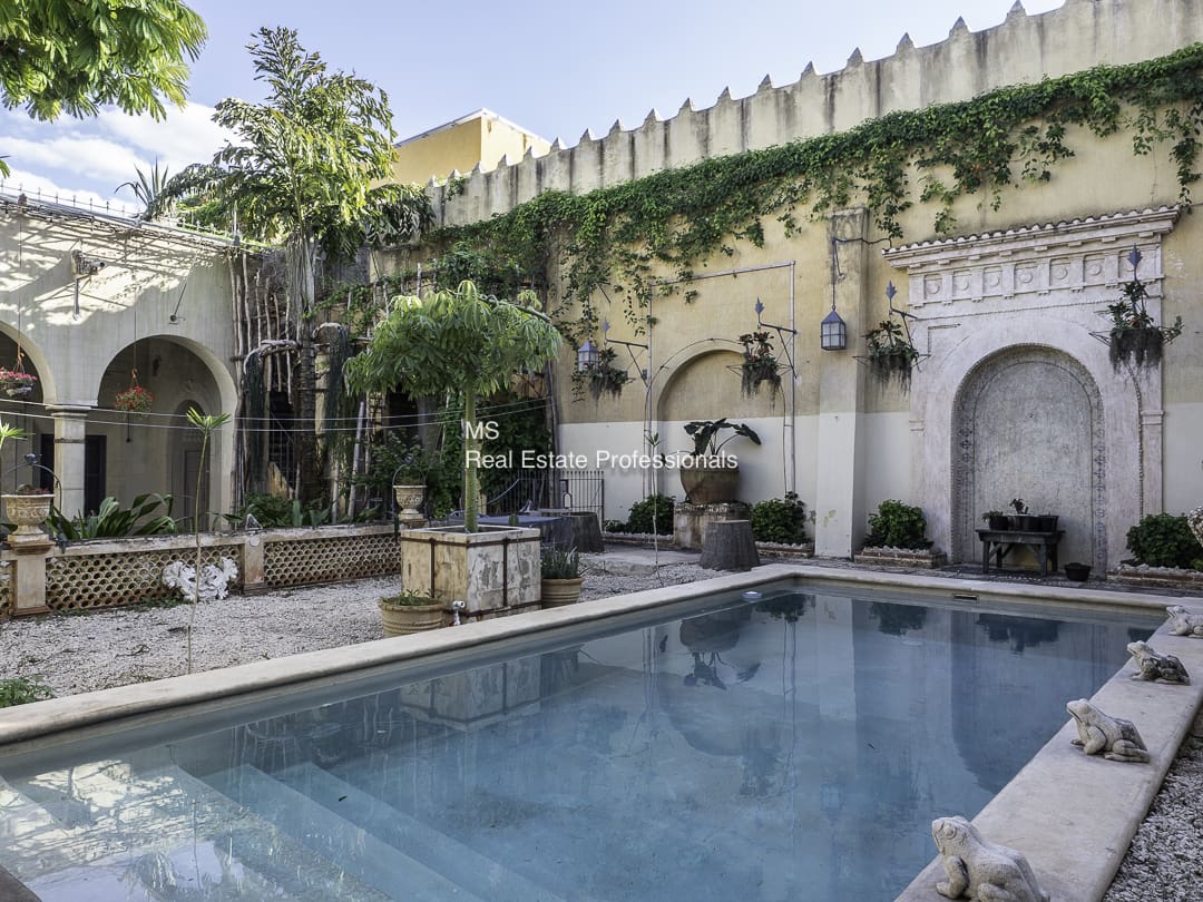 A serene courtyard with a pool and greenery.