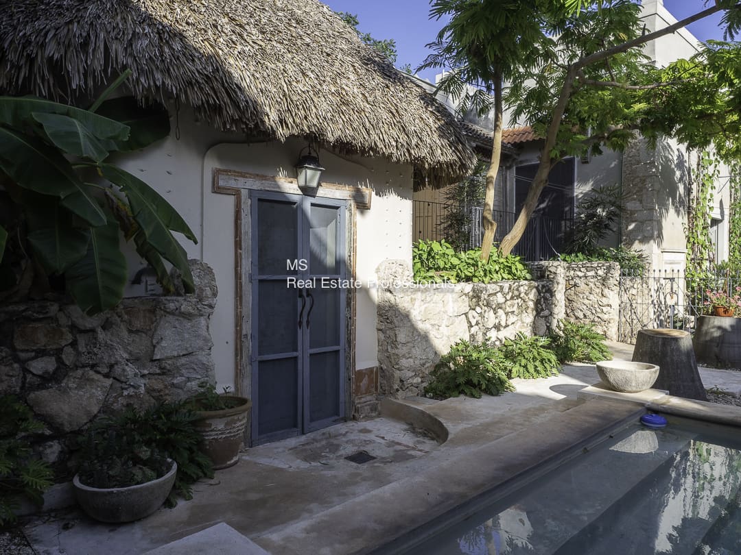 A rustic stone house with a thatched roof and blue door.