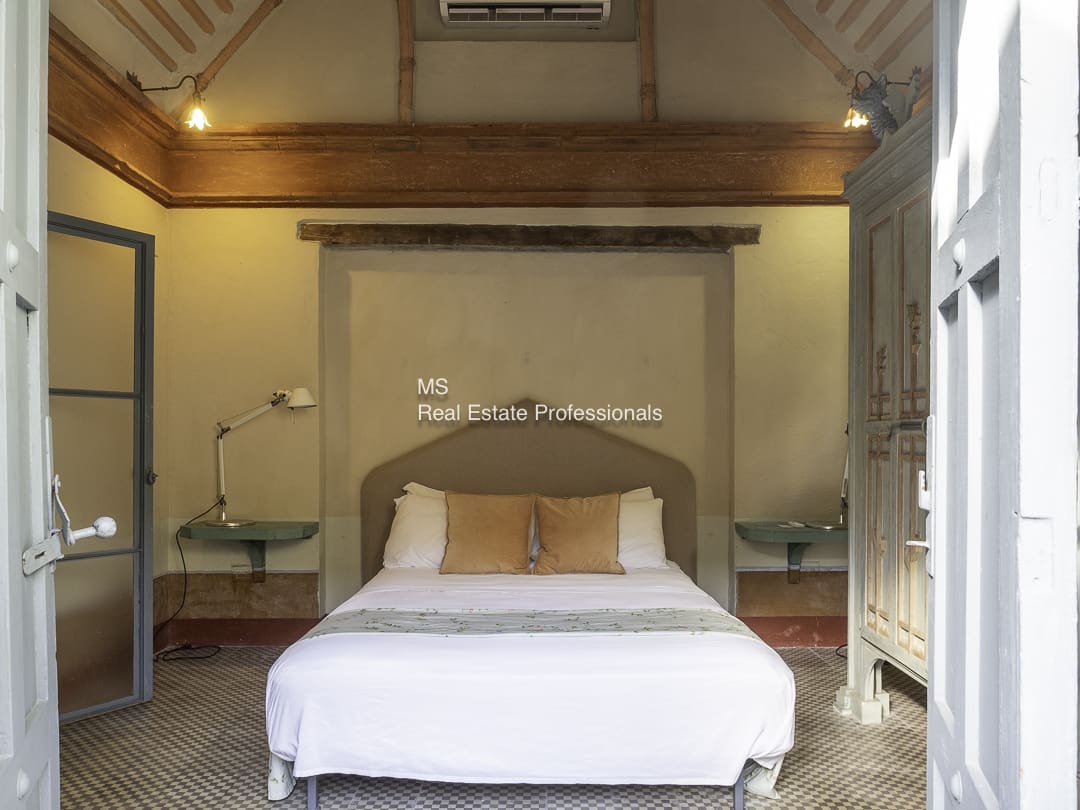 Cozy bedroom with wooden beams and white bedding.