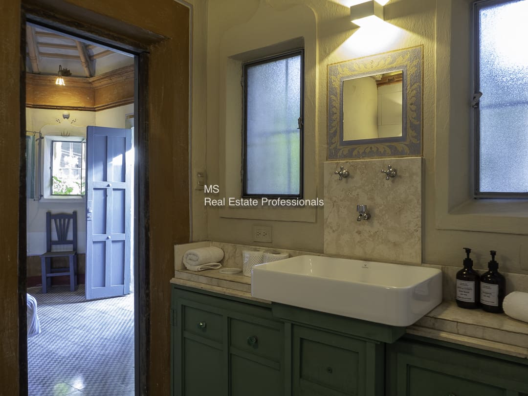A rustic bathroom with a white sink and wooden door.