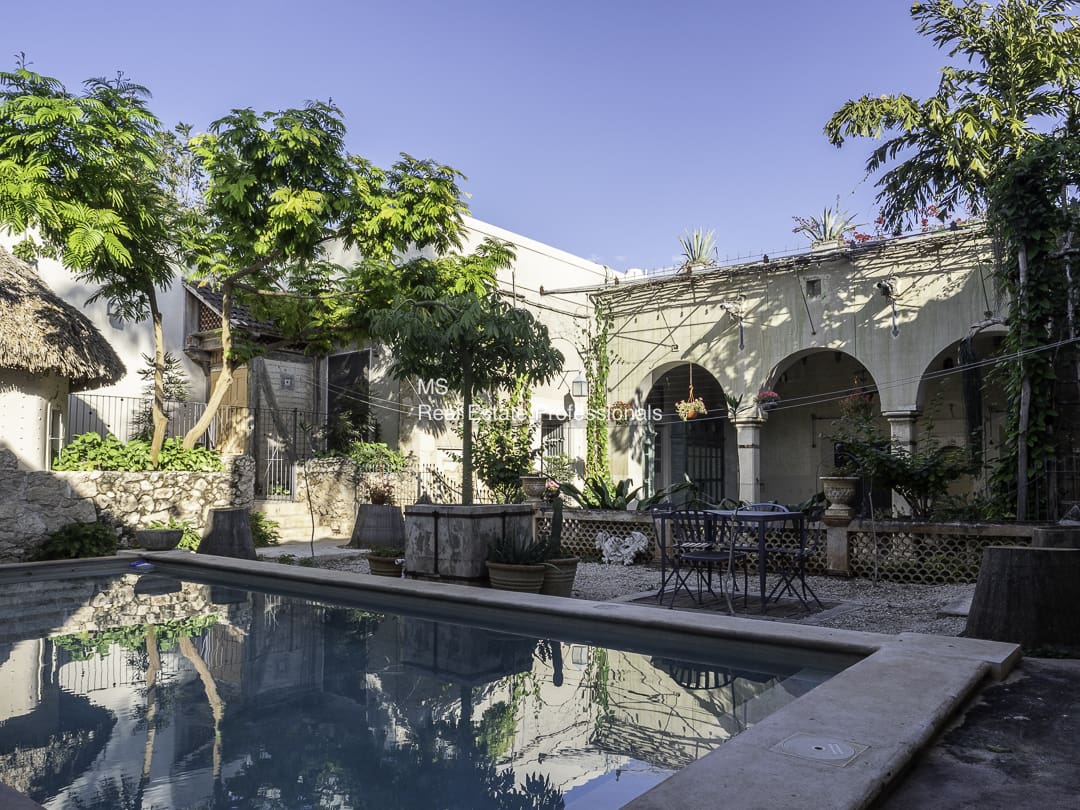 Historic courtyard with arches and a swimming pool.
