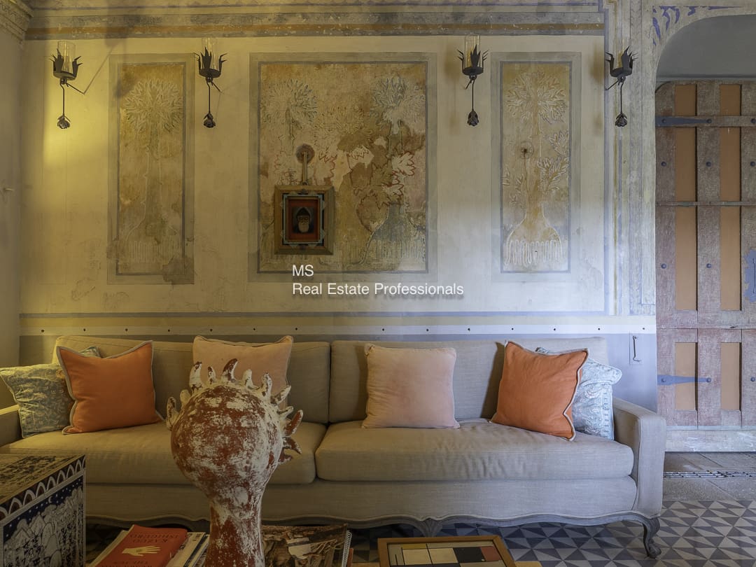 Cozy beige sofa with orange cushions against a vintage wall.