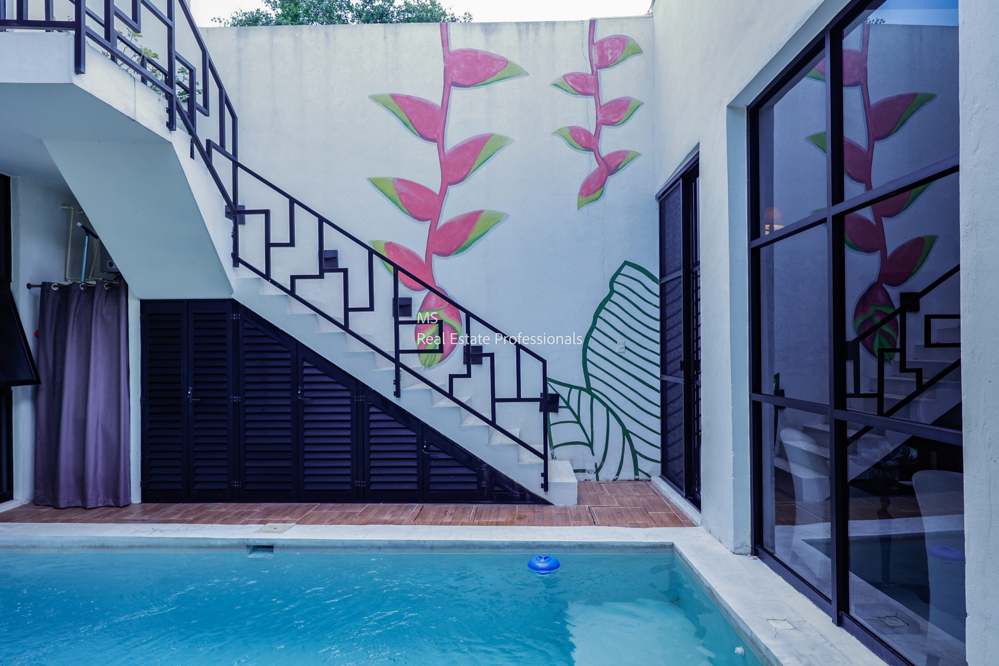 A modern outdoor pool next to a staircase with pink leaf wall art.