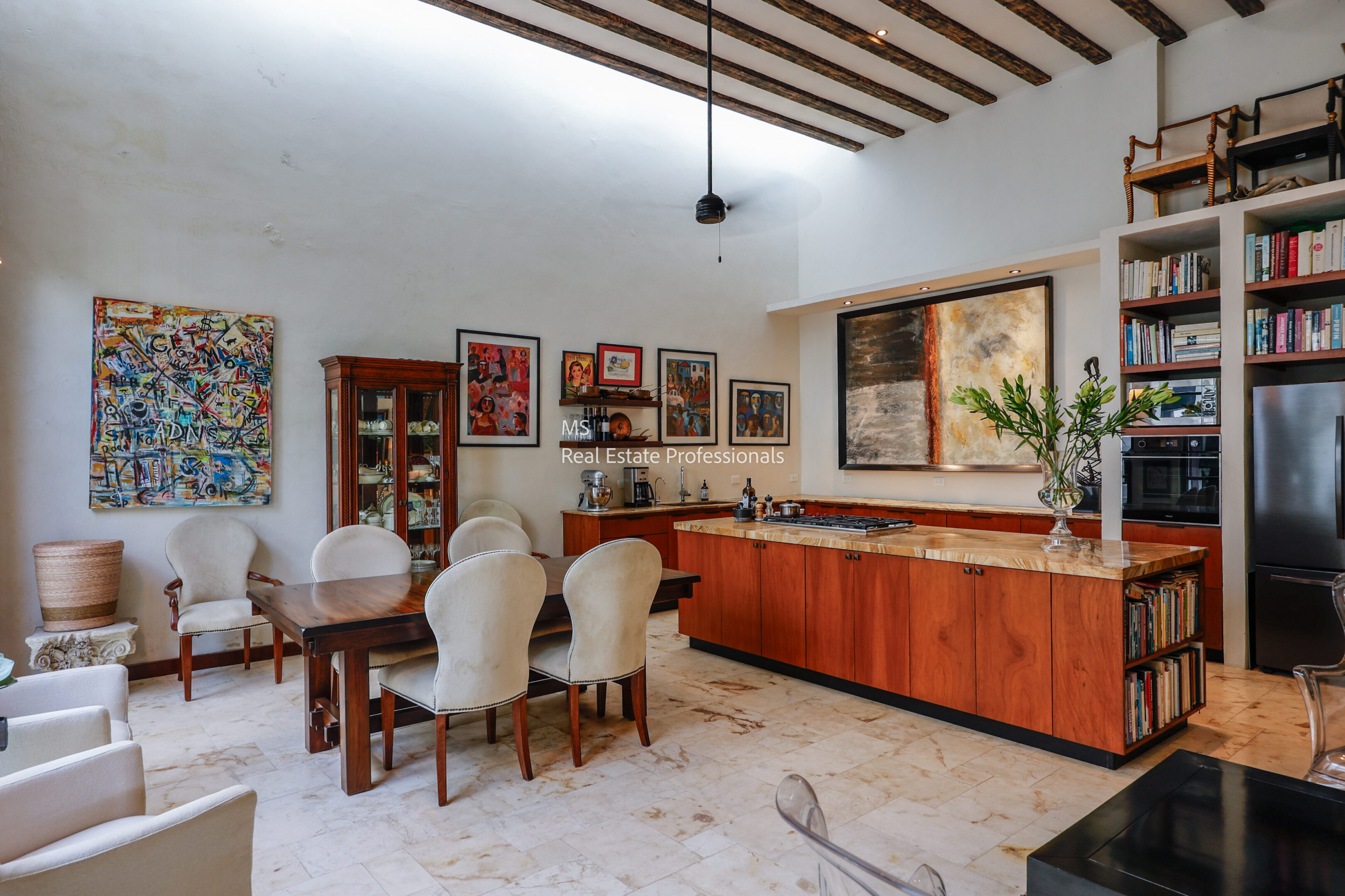 A stylish dining room with wooden ceiling beams and art-filled walls.