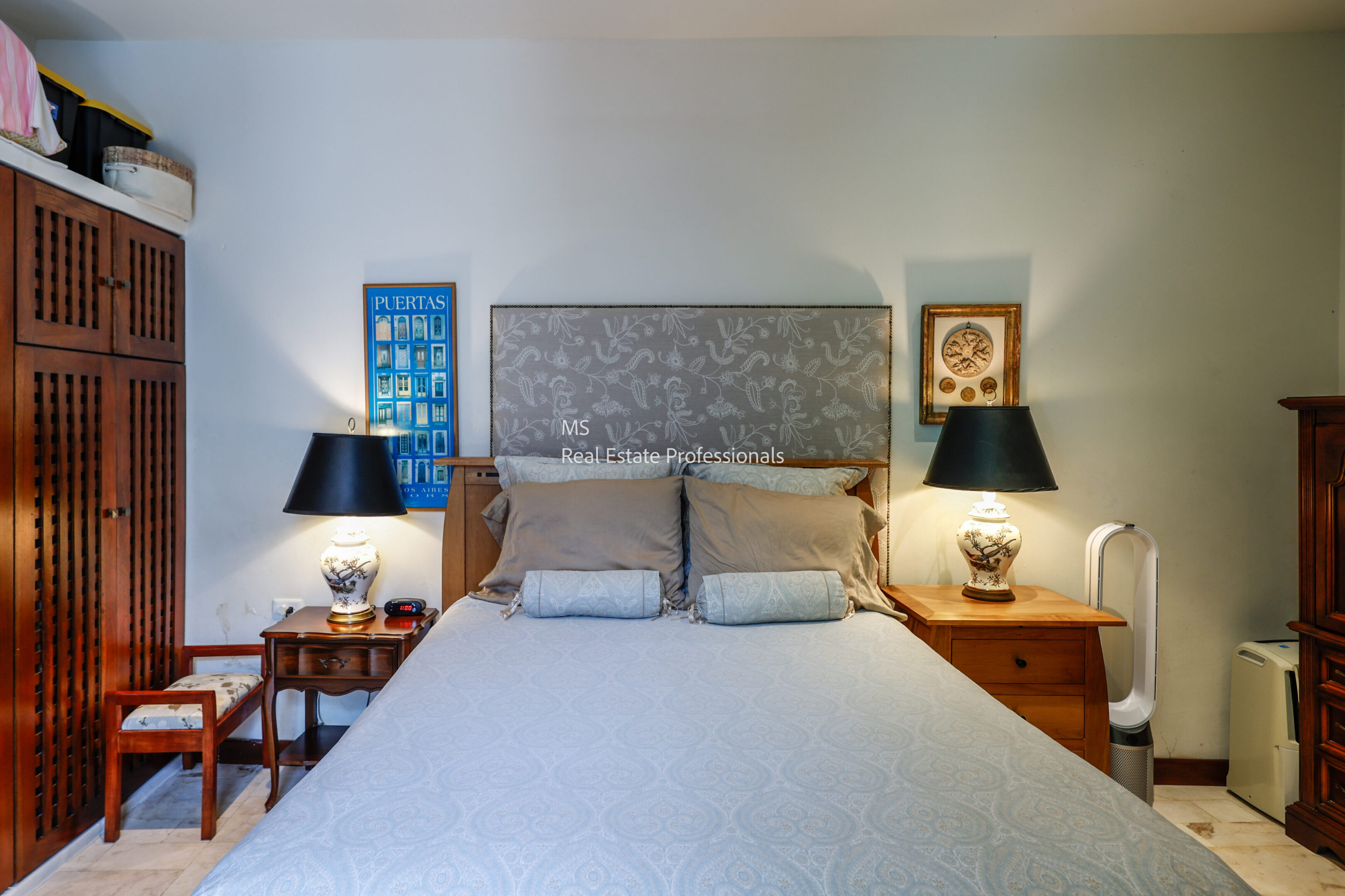 A cozy bedroom with a patterned headboard and bedside lamps.