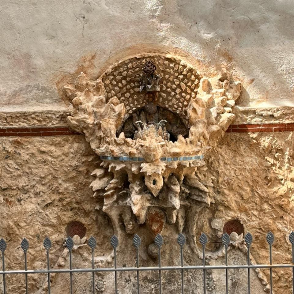 An intricately carved stone balcony with honeycomb patterns on a historic building.