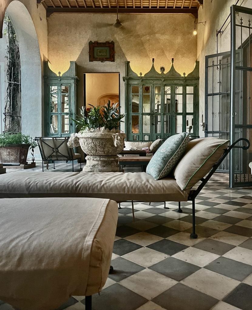 Elegant outdoor seating area with cushioned chaise lounges and potted plants.