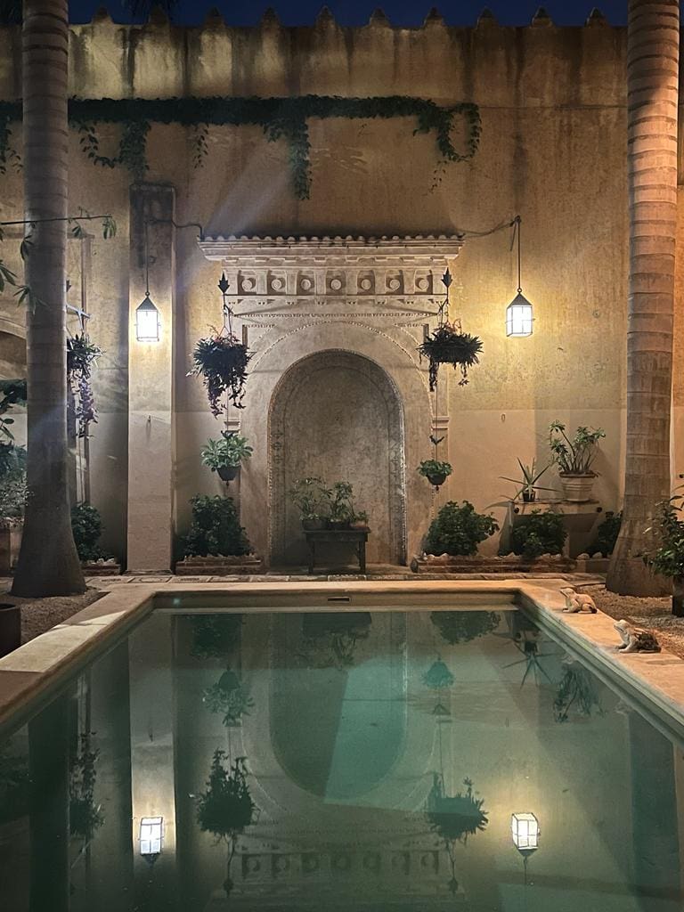A cozy courtyard with a small pool and warm lighting at night.