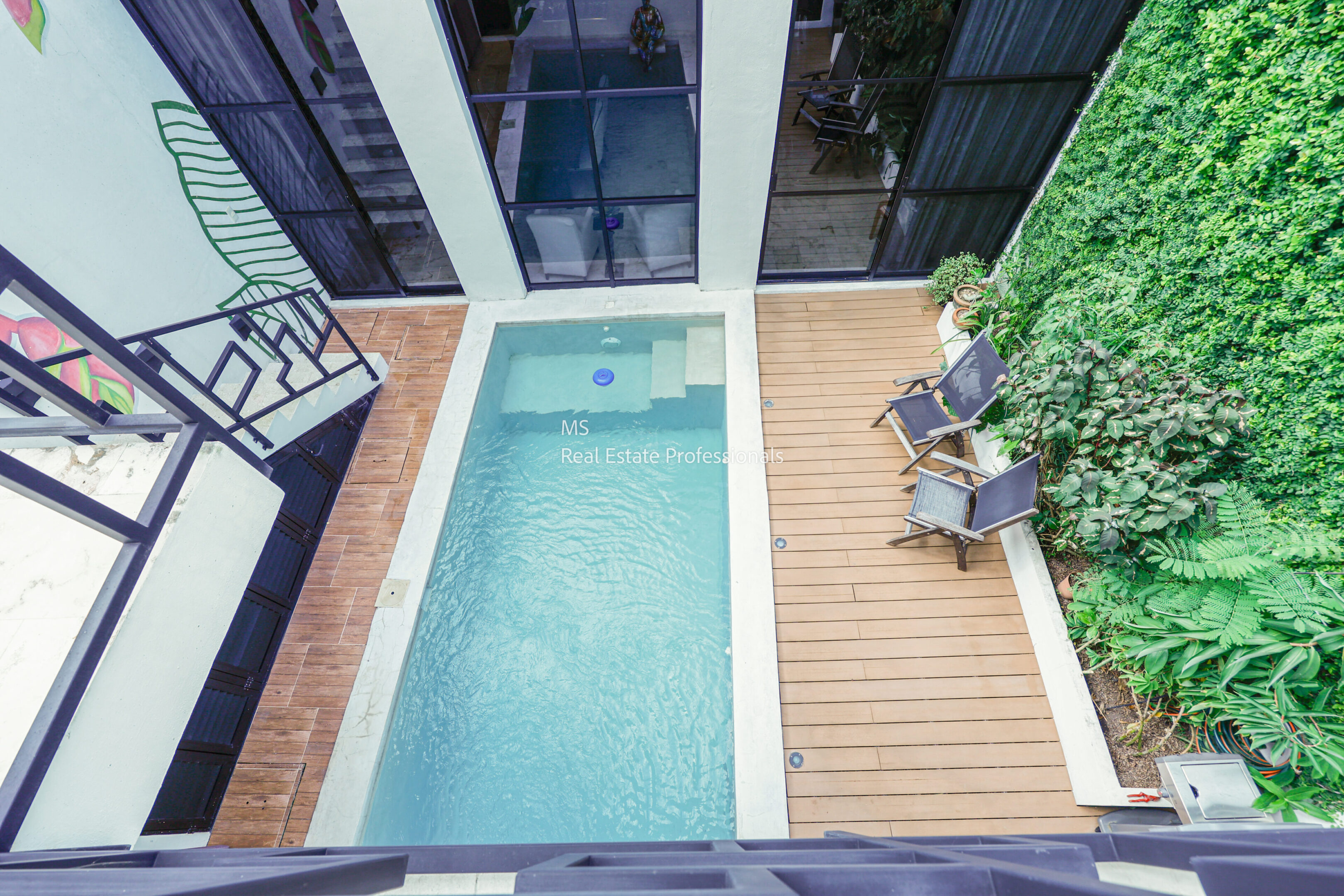 Overhead view of a modern pool with lounge chairs on a wooden deck.