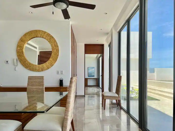 Modern dining room with large windows and ceiling fan.