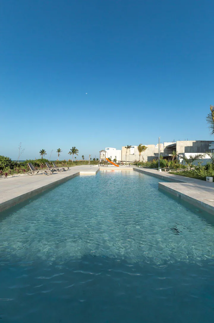 A long rectangular pool with clear water under a bright blue sky.