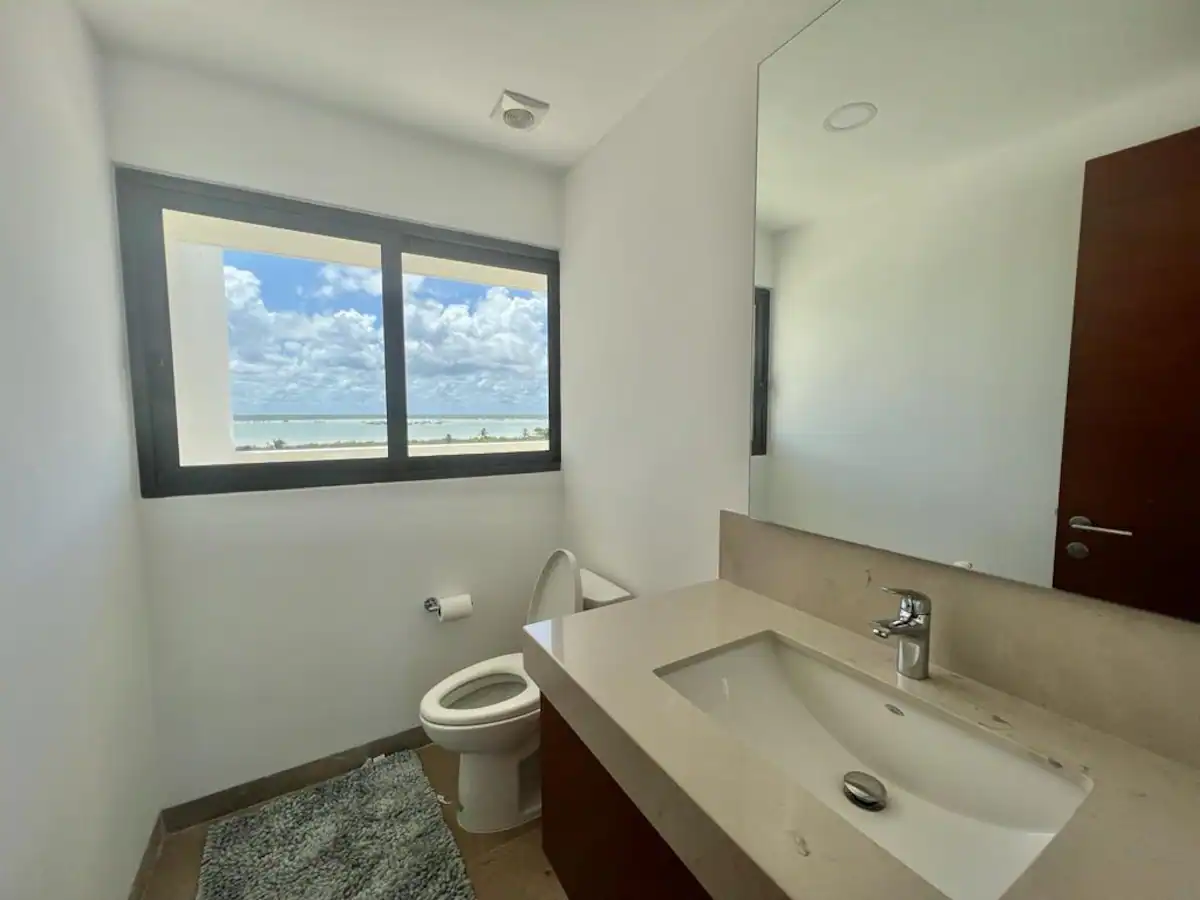 A modern bathroom with a large window showing a blue sky.