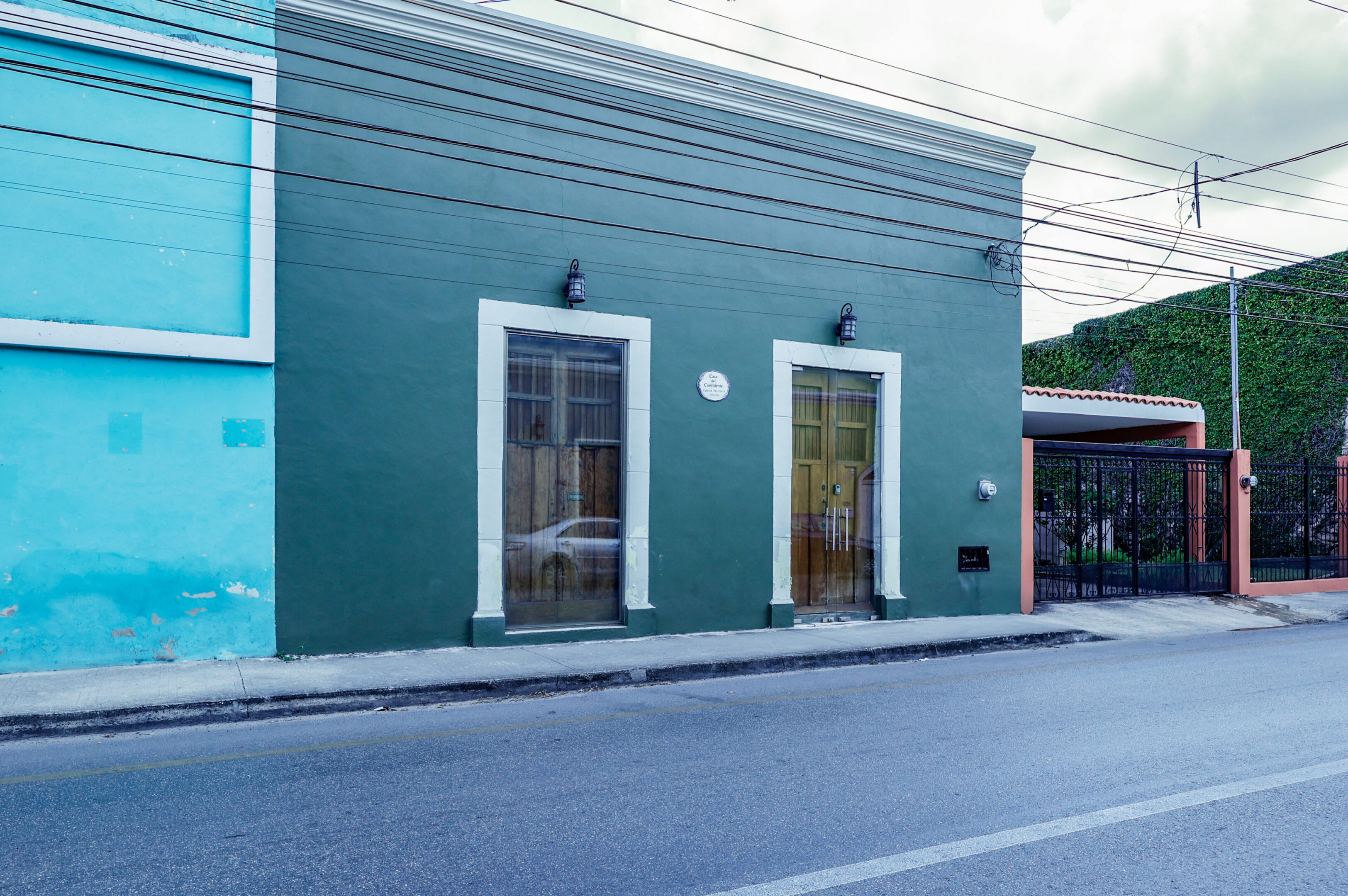 A green building with two windows on the side of it.