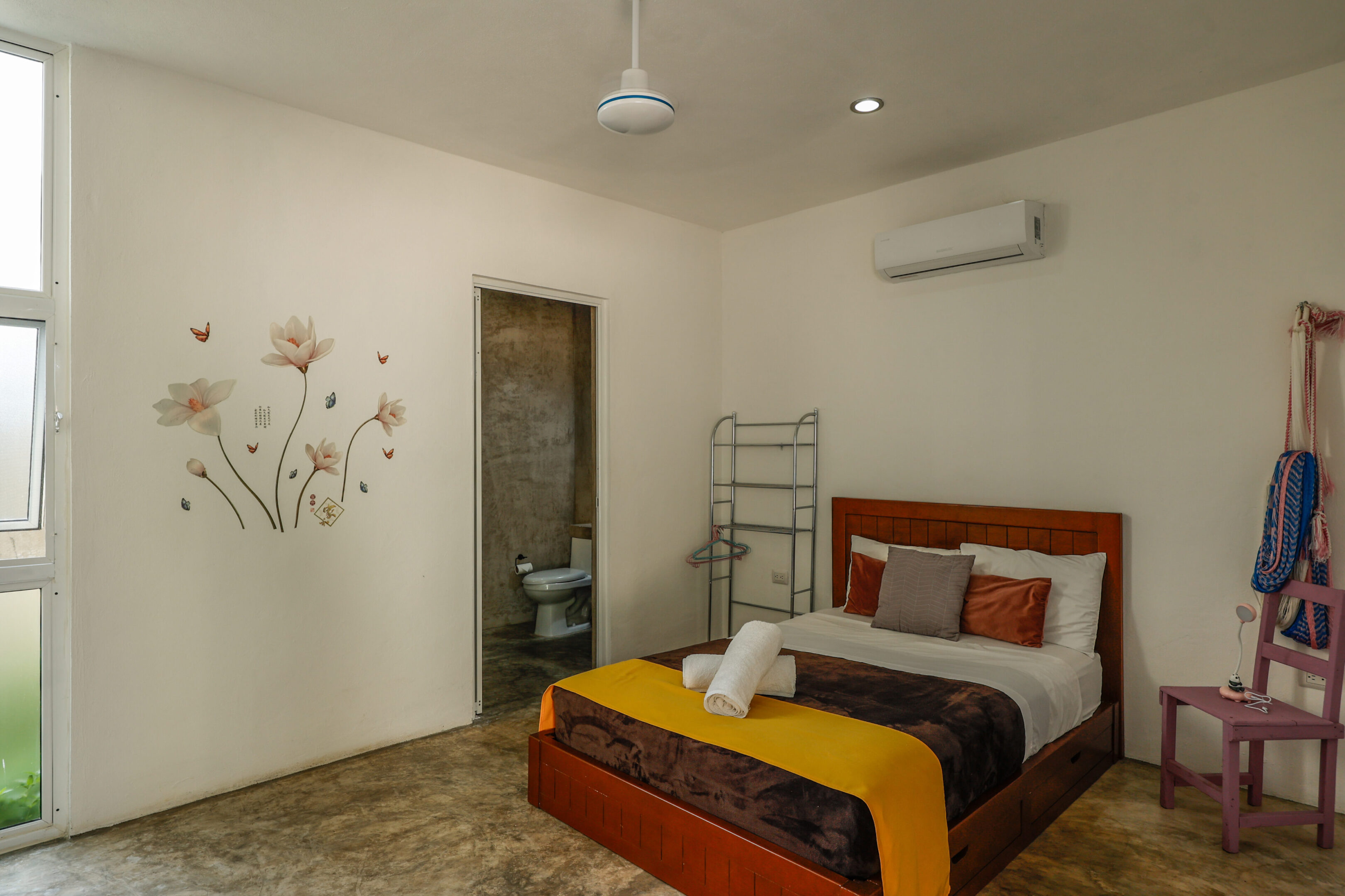 A bedroom with a bed, wall and ceiling fan.