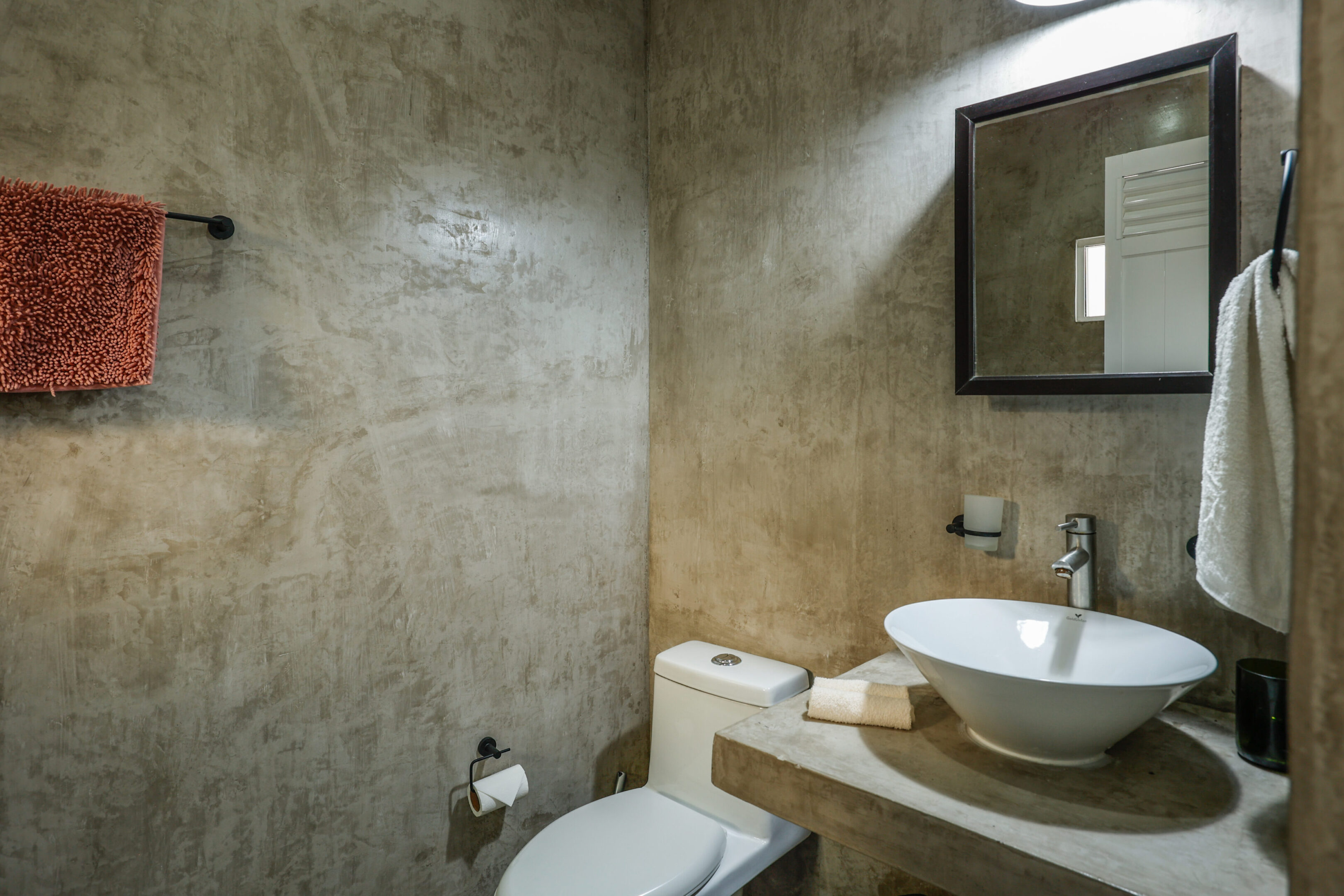 A bathroom with a toilet, sink and mirror.