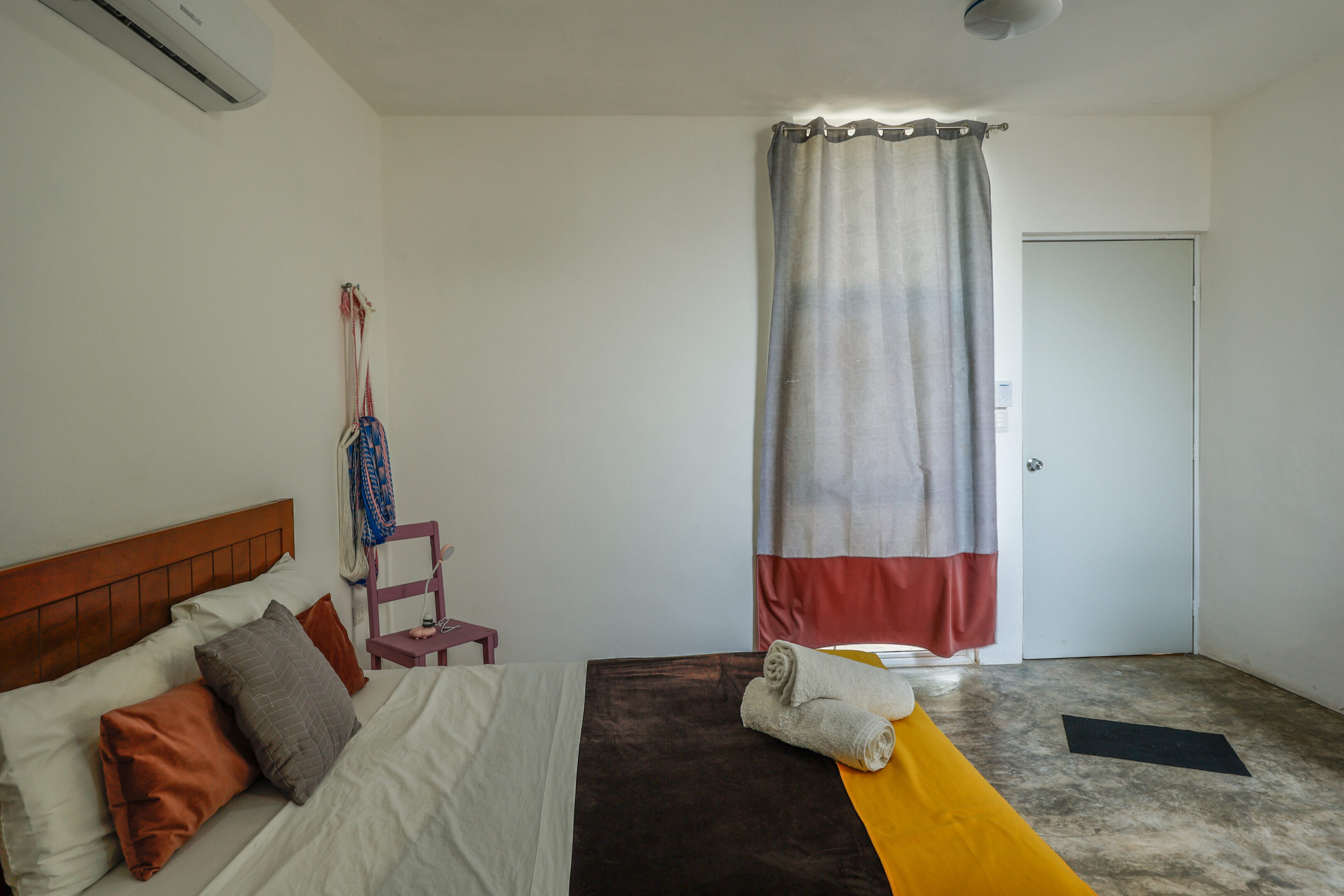A bedroom with a bed, chair and window.