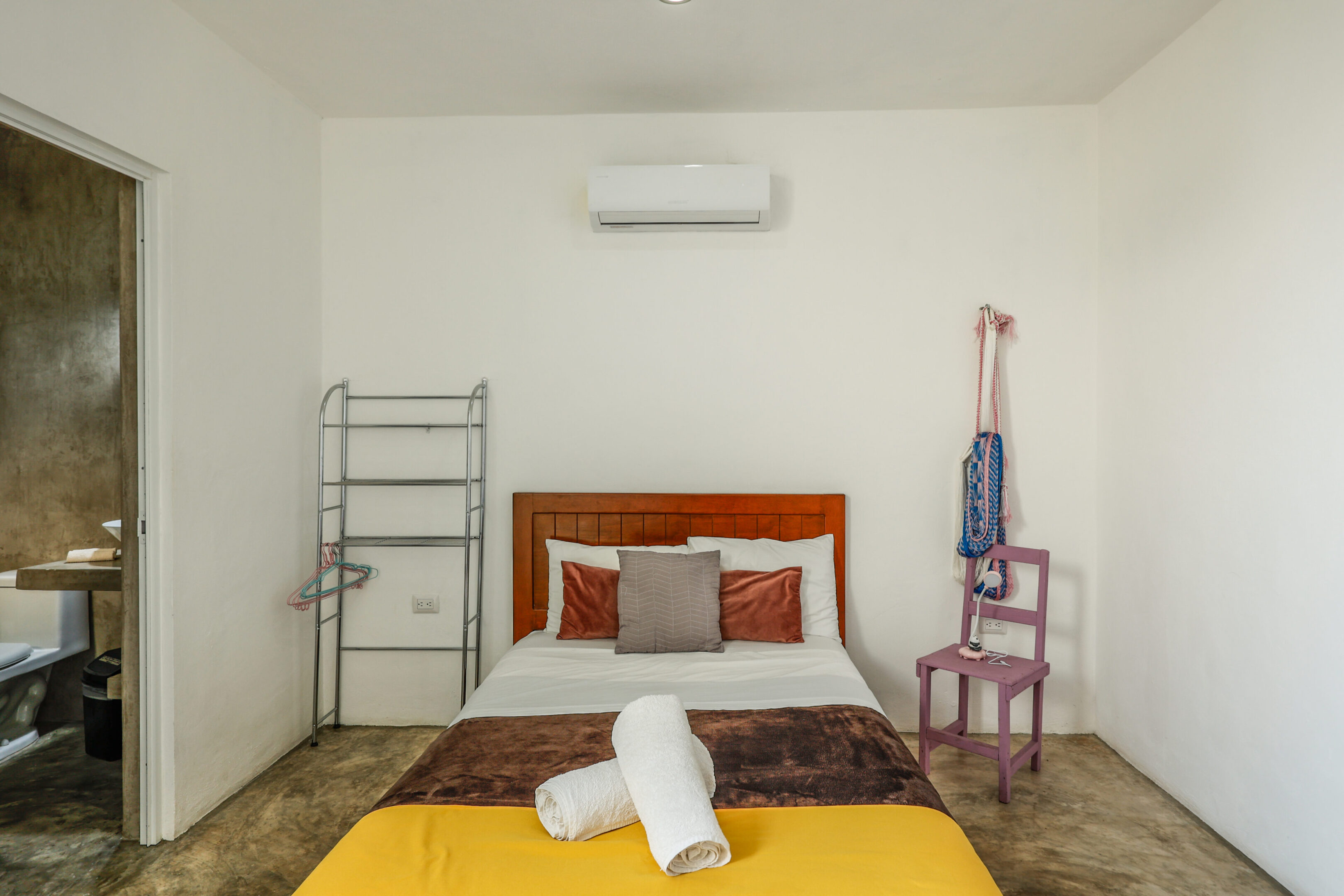 A bed room with a yellow blanket and white sheets