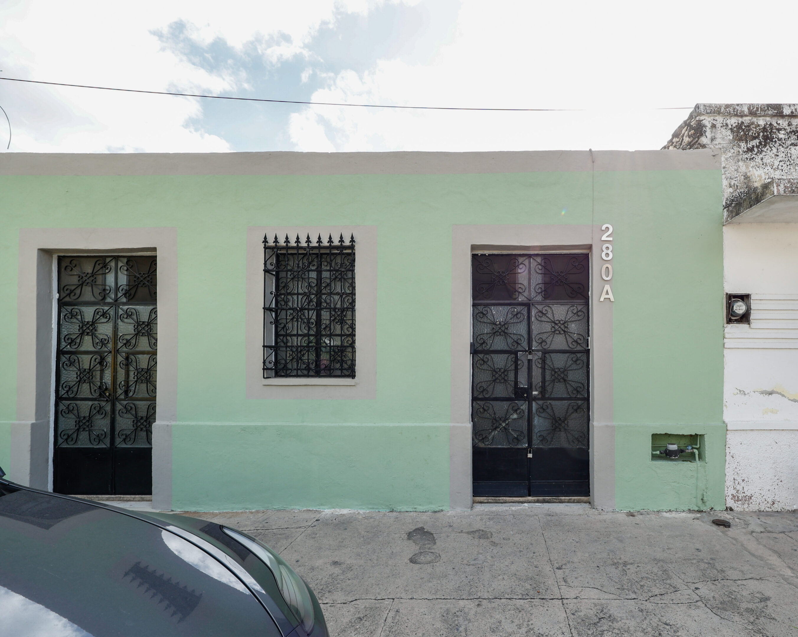 A green building with two black doors and windows.