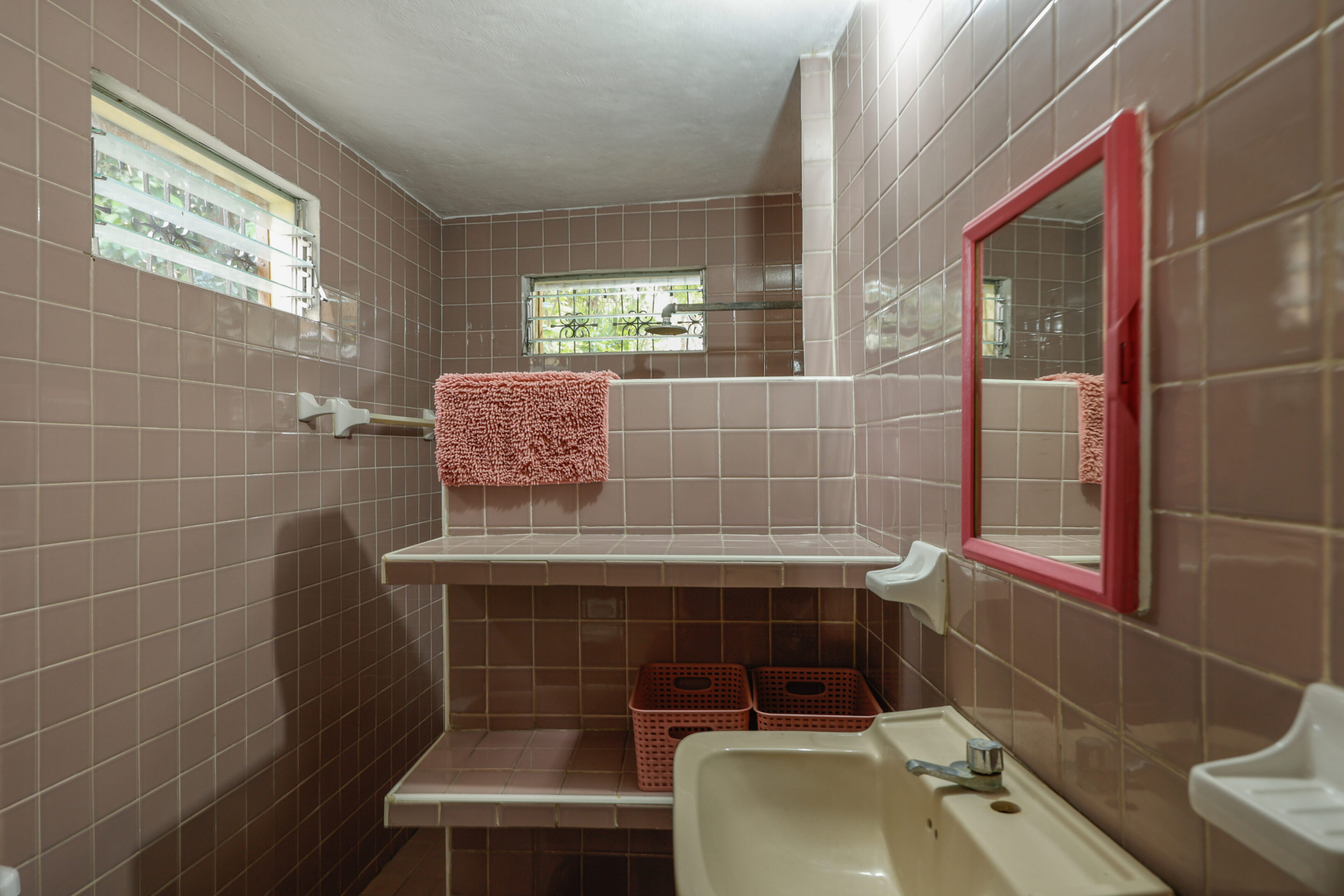 A bathroom with pink tiles and a sink.