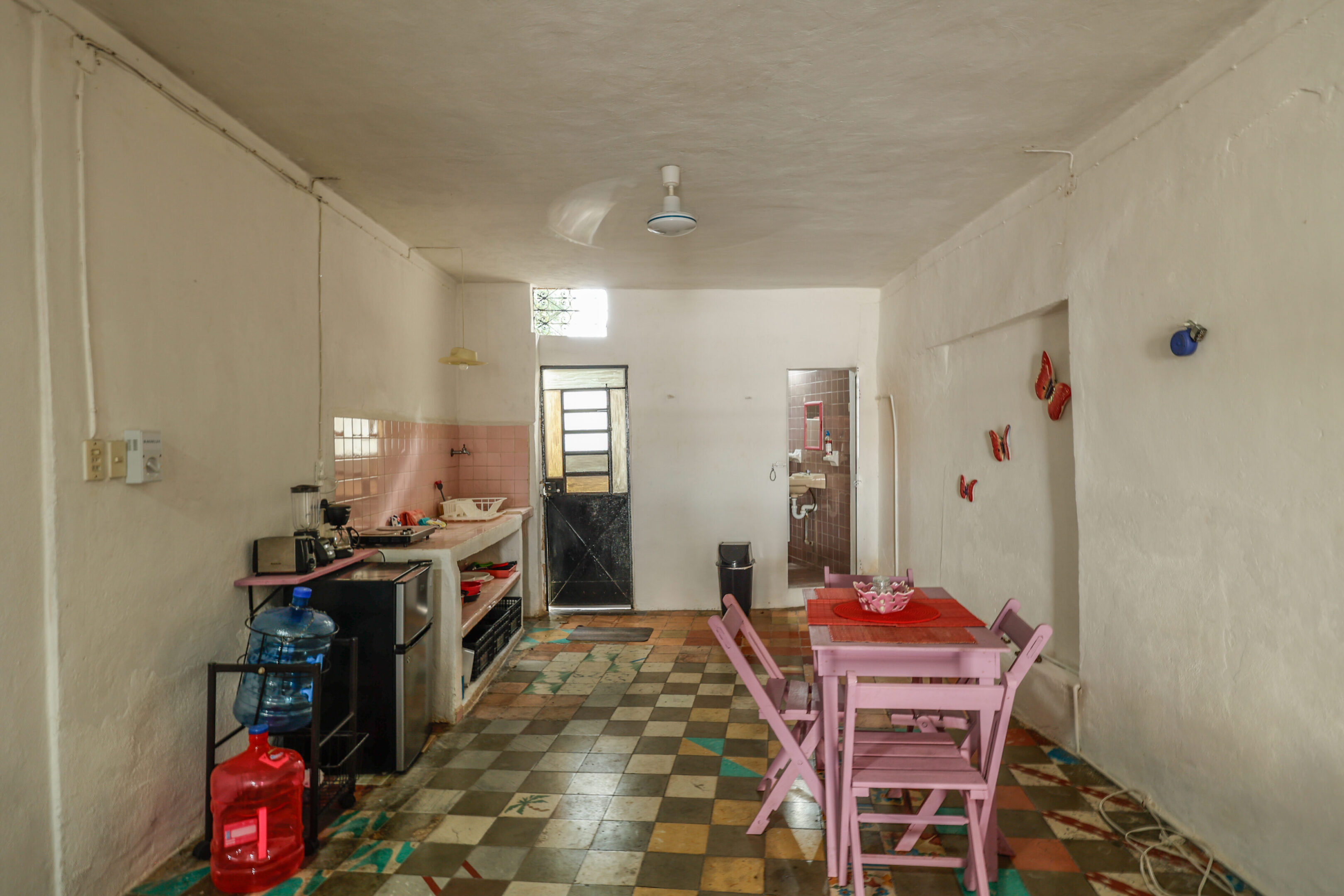 A kitchen with pink chairs and checkered floor