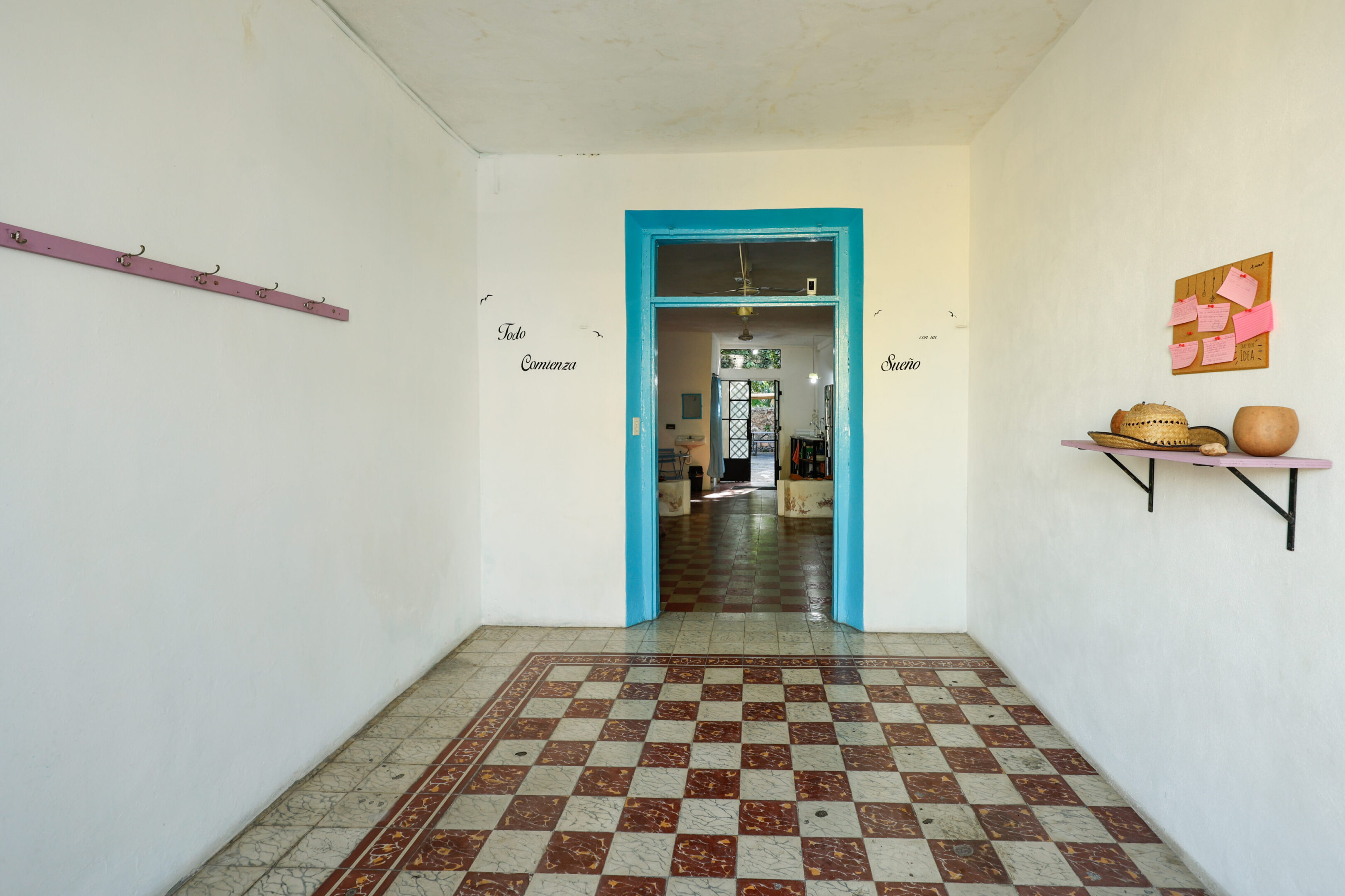 A hallway with a blue door and checkered floor.