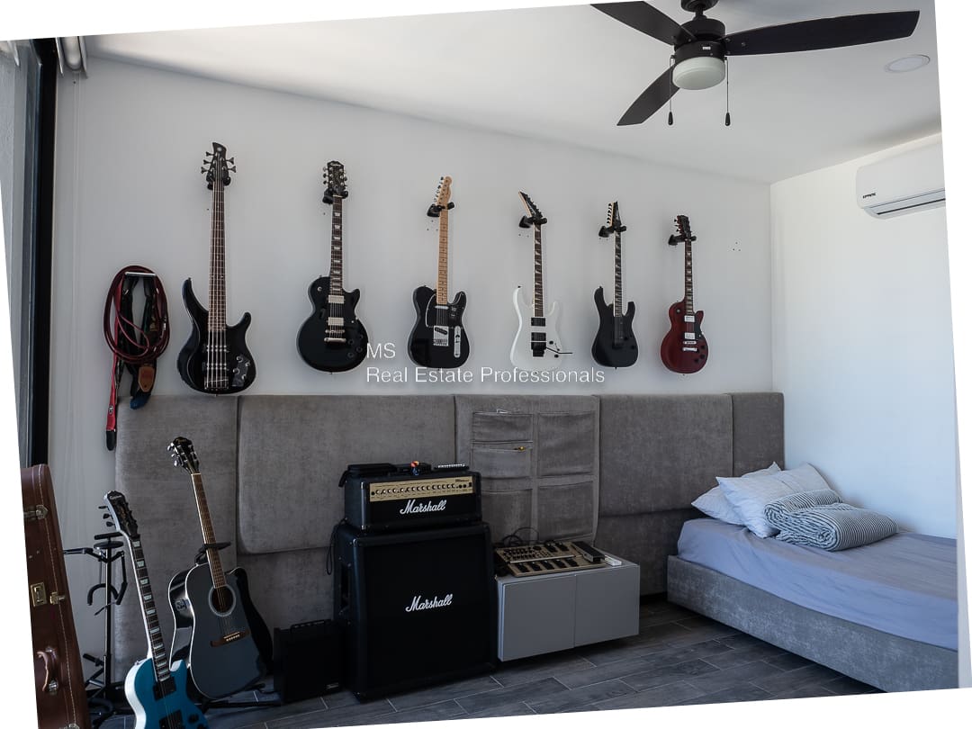 A room with many guitars hanging on the wall