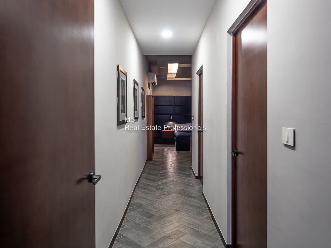 A hallway with two doors and three pictures on the wall.
