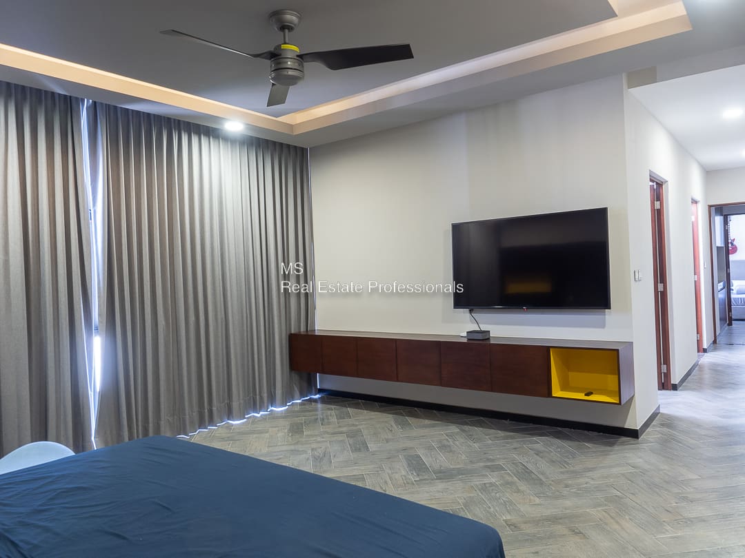 A bedroom with a bed, tv and a window.
