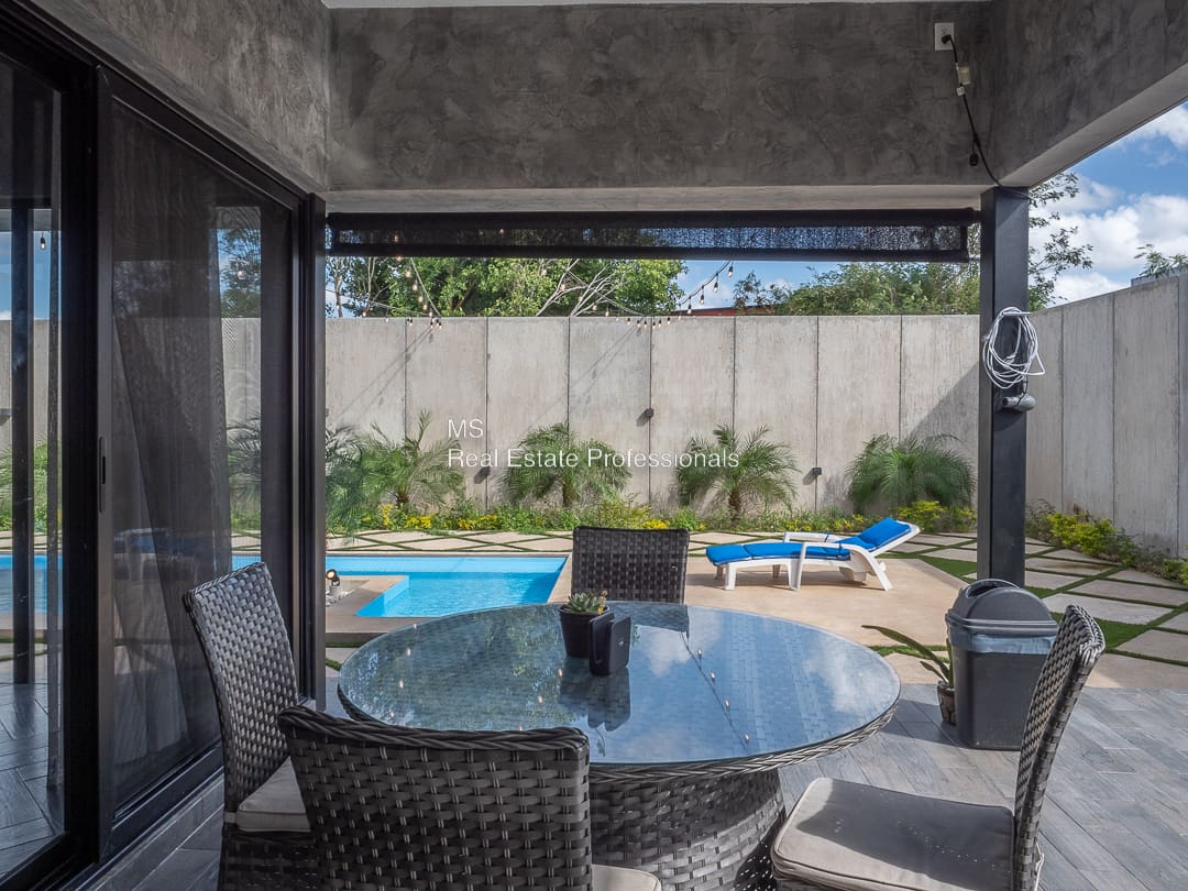 A patio with chairs and table in the middle of an outdoor area.