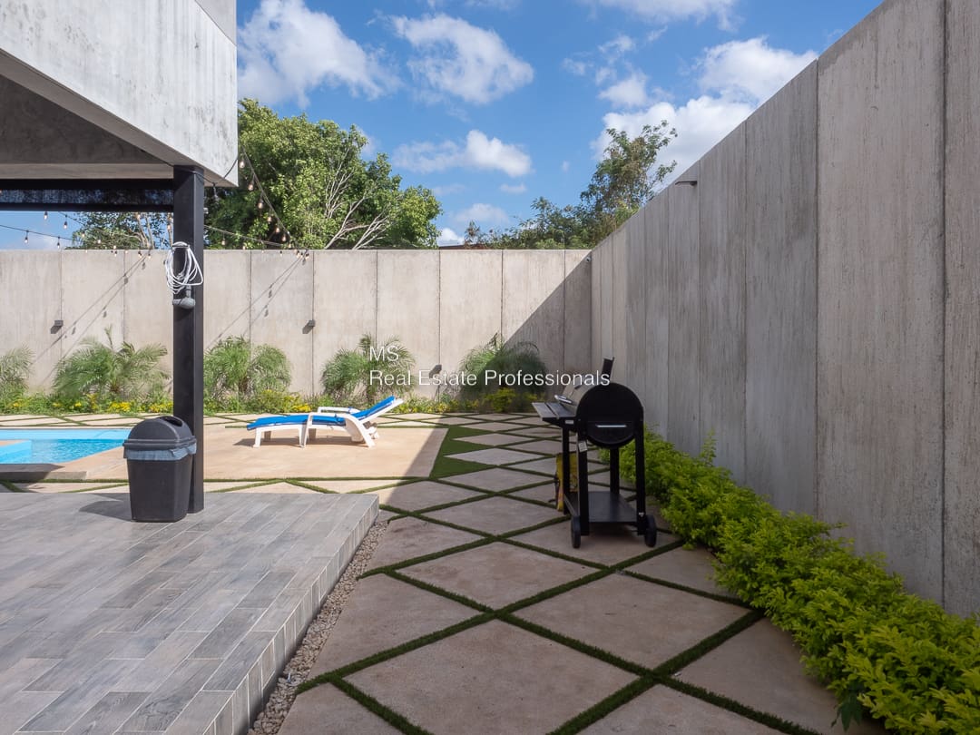 A patio with grass and concrete walls