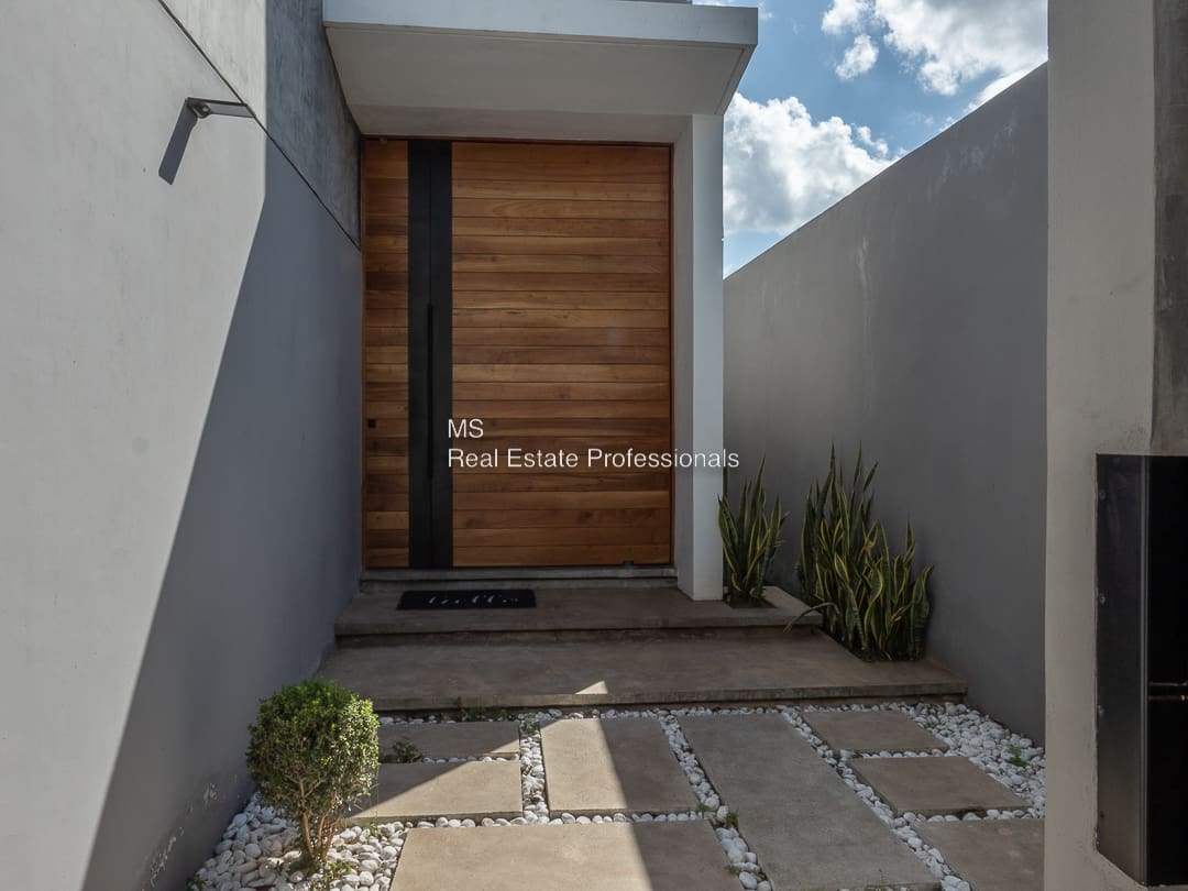 A modern house with a wooden door and stone walkway.