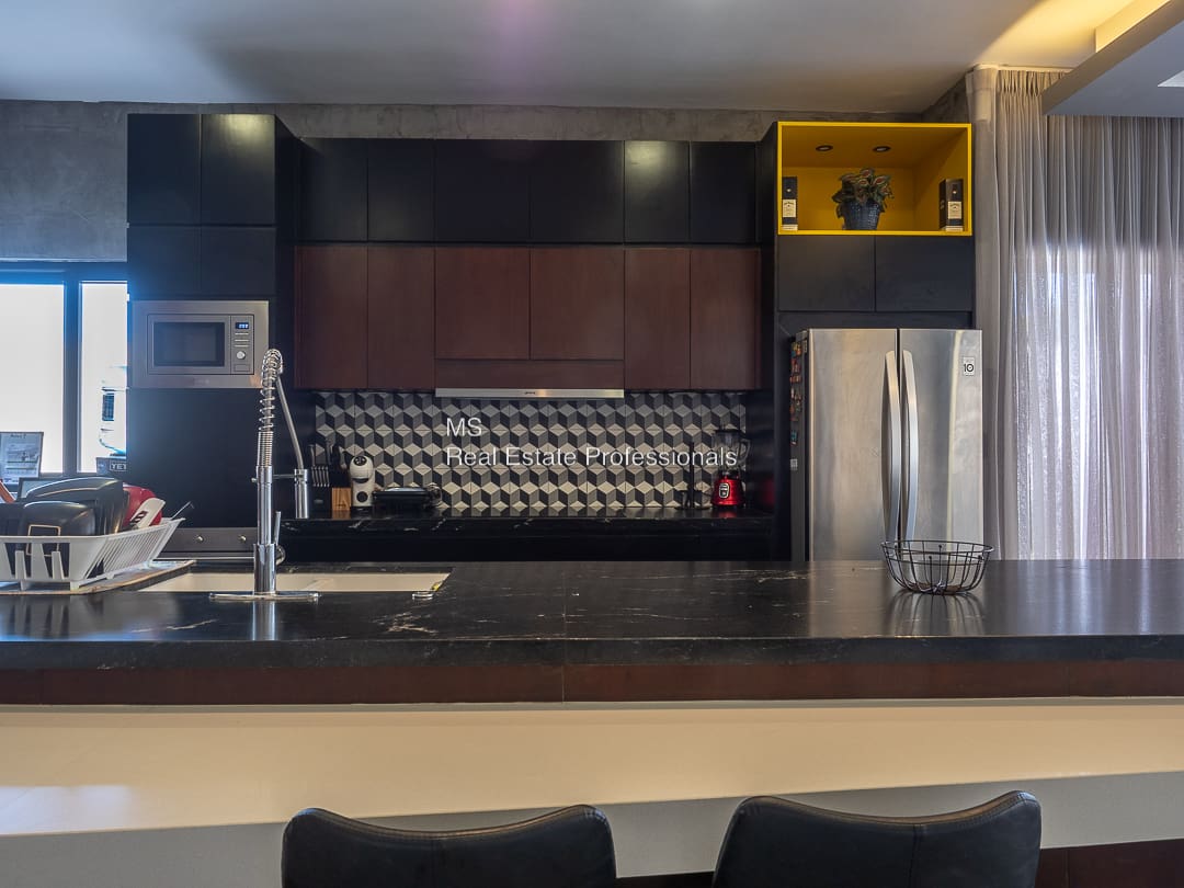 A kitchen with black counter tops and stainless steel appliances.